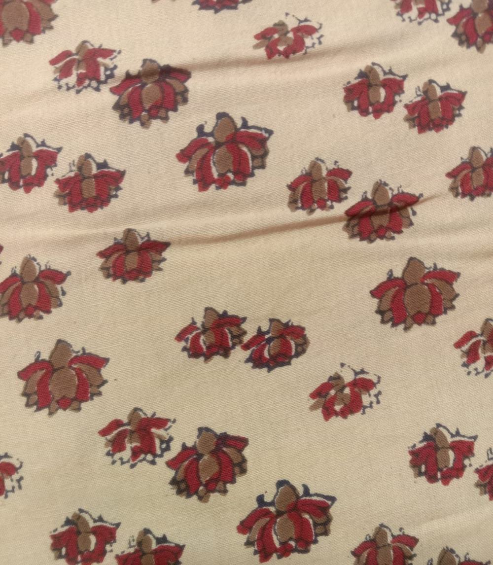 Hand block printed cotton in a small lotus motif, red and tan on cream.