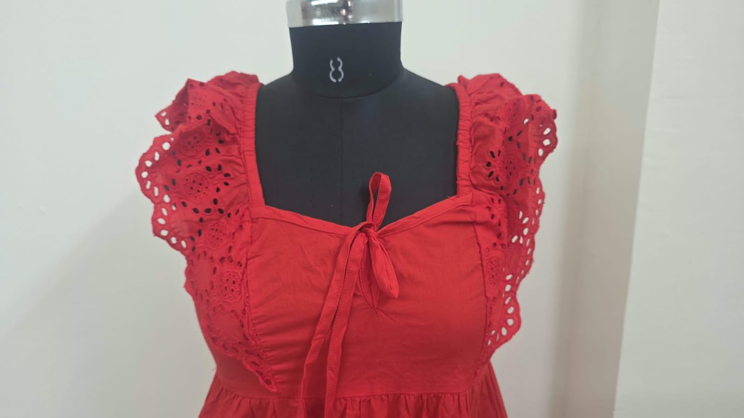 Cutwork eyelet frill at the shoulder of a red cotton dress.