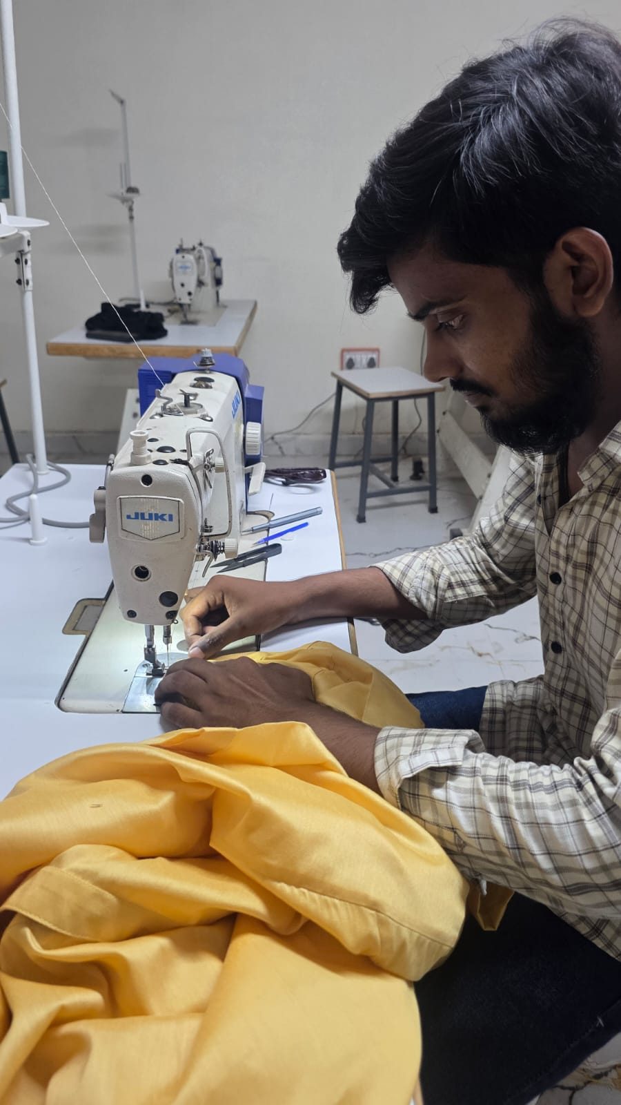 A tailor stitching yellow silk at a Juki machine.